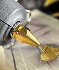 Industrial High Temp Hot Glue Sticks 10 Inch Light Amber for Packaging dispensing onto wood surface, close-up shot