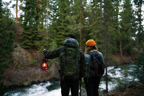 Hikers in forest holding 12 Inch Hurricane Lantern With Durable Red Finish For Camping And Emergencies, classic outdoor gear