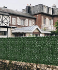 Faux Ivy Privacy Fence Screening Expandable Outdoor Greenery Roll Easy Install For Garden And Patio Realistic Fake Hedge Wall Panels 157.5 By 39.4 Inches Ideal Gate Cover And Balcony Yard Decor in front of a brick house.