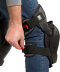 Person adjusting strap on impact absorbing gel knee pads with thigh stabilization for flooring and roofing, lightweight TPE gel.