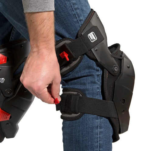 Person adjusting strap on impact absorbing gel knee pads with thigh stabilization for flooring and roofing, lightweight TPE gel.