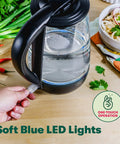 1.7 Liter Glass Electric Kettle That Boils Seven Cups In Just Six To Seven Minutes With Soft Blue LED Lights, Cordless Portable Water Heater, Auto Shut Off, Black Finish on a table with vegetables.