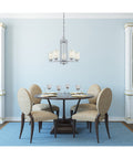 Dining area with Five Light Indoor Chandelier In Chrome With White Linen Glass Hansen Model, table and chairs underneath.