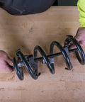 Heavy Duty Coil Spring Compressor With Detent Locks And Built In Safety Gauge in use compressing a coil spring on wooden table