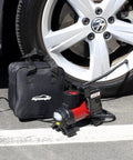 12V DC Portable Air Compressor With Digital Pressure Gauge And Bright Led Light For Cars Bikes And Midsize Suv Heavy Duty Tire Inflator Pump next to a car tire.
