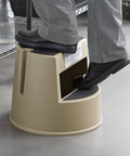 Person using Mobile Heavy Duty Plastic Step Stool With Wheels, 16 Inch Beige, 350 Pound Capacity, Nonslip Steps in an indoor setting.