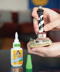 Person using Clear Gel Super Glue For All Purpose Bonding Fast Setting And No Run Formula Great For Glass Plastic Wood Ceramic And More Ideal For DIY Projects And Household Repairs 20 Gram Pack on a lighthouse model.