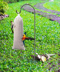Three Pack Finch Sock Feeders Budget Friendly With Thistle Seed Bags For Outdoors And Garden on metal pole in grassy area