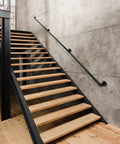 Badass 12 Foot Matte Black Stair Handrail Wall Mount Pipe Style Metal Grab Bar Non Slip Grip Built Tough For Indoor Steps And Outdoor Decks, mounted on wooden staircase.