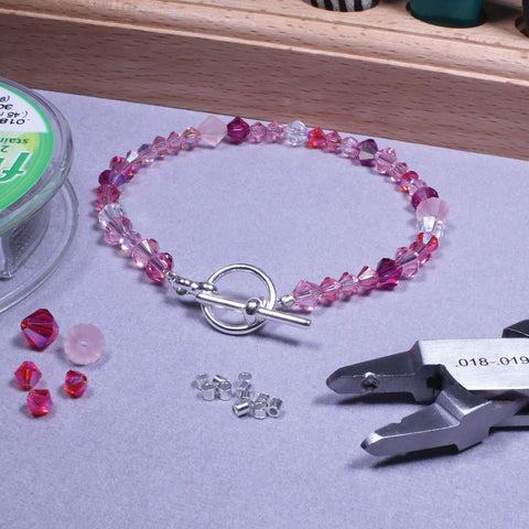 Epic All In One Crimping Kit With Pliers, 500 2x2 mm Crimp Tubes In Silver Gold Copper, And 21 Strand Flex Rite Wire displayed with bracelet