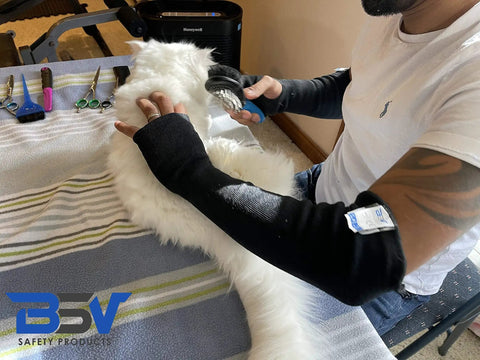 Person wearing Kevlar Arm Protection Sleeves with Finger Opening for industrial tasks and pet grooming, 18 inch black arm guards.