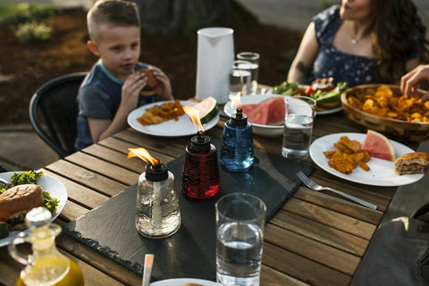 Lit Red White And Blue Glass Tabletop Torches Set Of Three for outdoor lighting on a patio table during a family meal