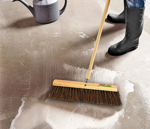 Heavy Duty 18 Inch Palmyra Bristle Push Broom For Garage Indoor Floor Sweep with wooden block on a wet concrete floor.