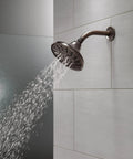 Five Setting Raincan Shower Head With H2Okinetic Spray in Venetian Bronze mounted on a tiled wall with water flowing
