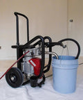 Professional Electric Airless Paint Sprayer Boasting PermaStroke Tech And 3300 Psi Thrust next to a blue paint bucket on a cloth floor.