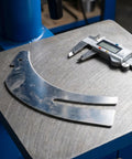 Rock Solid Table Saw Riving Knife Metal Splitter Guard on workshop table with calipers for precise measurement.