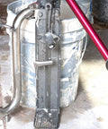 Pro Grade Compound Pump Gooseneck for Drywall Mud Loader, heavy-duty stainless steel next to mud bucket.