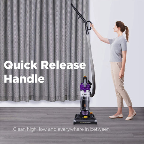Front view of purple Eureka PowerSpeed bagless upright vacuum being used to clean a floor near gray curtains.