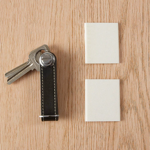 Self-adhesive door corner foam seals in white; two square pads shown with keys on a wooden surface.