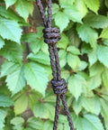 Close-up of 3mm Paracord With Textured Posi Lock Ninja Black Color Made In USA, showing detailed knotting against a leafy background.