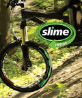 Mountain bike wheel in forest with "slime inside" logo, illustrating use of Bike Tube Puncture Repair Sealant For All Bicycles Eight Ounce Bottle Non Toxic Eco Friendly Quick Seals Punctures Up To One Eighth Inch Prevents Flats And Gets You Rolling No More Flats.