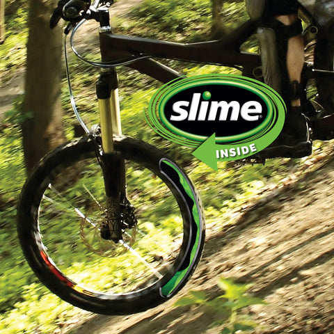 Mountain bike wheel in forest with "slime inside" logo, illustrating use of Bike Tube Puncture Repair Sealant For All Bicycles Eight Ounce Bottle Non Toxic Eco Friendly Quick Seals Punctures Up To One Eighth Inch Prevents Flats And Gets You Rolling No More Flats.