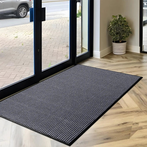 Heavy Duty Rubber Door Mat 3 By 5 Feet For Indoor Outdoor Use Waterproof And Easy Clean Entry Mat Traps Dirt And Moisture Ideal For High Traffic Patios Garages And Commercial Entrances placed in a doorway with a plant nearby.