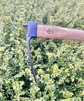 Close-up of 14 Inch Tough As Nails Narrow Hoe with Oak Wood Handle, showing Japanese carbon steel blade, in garden setting.