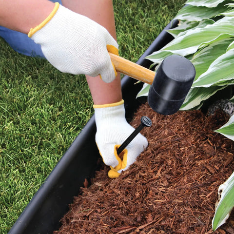Installing Pro Grade Landscape Edging Kit 5 Inch By 20 Foot Heavy Duty Garden Border with spike and mallet in garden bed