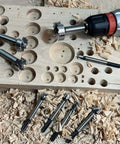 Overhead view of CORTOOL 16-piece Forstner bit set with hex shanks beside a Metabo drill on wood shavings.