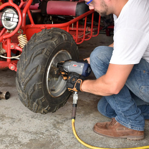 Person using Half Inch Pneumatic Impact Wrench With 750 Ft Lbs Torque Three Speed Regulator on ATV wheel
