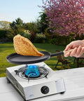Preseasoned 8 Inch Frying Pan Skillet With Detachable Wooden Handle in outdoor setting, frying a crepe on a gas stove