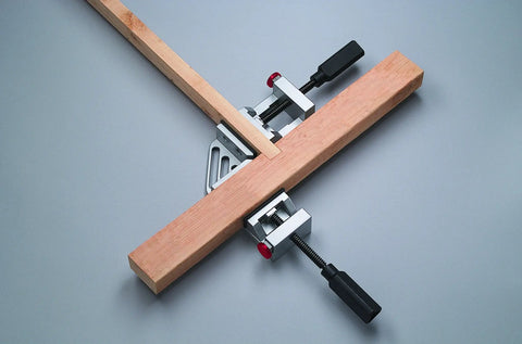 Quick-Jaw Right Angle Corner Clamp for Cabinets and Boxes in use, clamping two wooden boards at 90 degrees, showing ergonomic handles