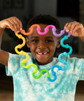 Plip Links Silicone Building Toys For Open Ended Creative Play A Fun Construction Set For Kids Aged 3 To 12 That Sparks STEM Skills Through Pattern Building And Preschooler Hands On Imagination, child holds rainbow silicone links