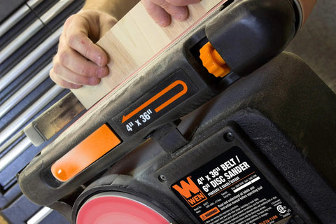 User sanding wood on Two In One Benchtop Belt And Disc Sander For The Home Workshop With Four By Thirty Six Inch Belt And Six By Six Inch Disc Cast Iron Base Belt Tilts Zero To Ninety Degrees 3600 RPM 4.3 Amp Motor Tension Release Lever For Easy Sandpaper Changes