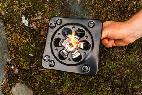 Portable Folding Camp Stove For Camping And Backpacking Easy Carry Ultra Light Steel Stove with flame, on the ground, in use.