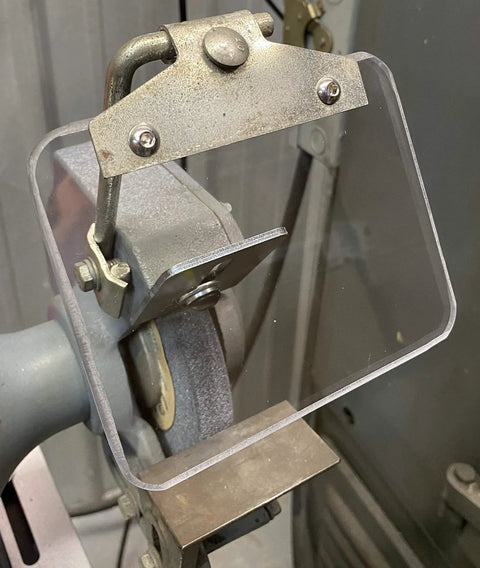 Dead Nuts Drop In Replacement Eyeshield For Bench Grinders featuring clear Lexan lens mounted on grinding machine.