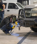 Person welding truck bumper with All Position Flux Core MIG Wire For Mild Steel Self Shielded Welds Through Rust Dirt And Paint Red