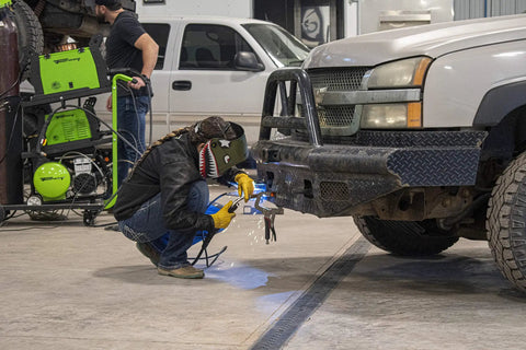 Person welding truck bumper with All Position Flux Core MIG Wire For Mild Steel Self Shielded Welds Through Rust Dirt And Paint Red