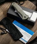 EDC Ready Folding Knife With D2 Steel Blade And Non Slip Fiberglass Handle displayed with pouch and card on wooden table