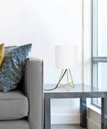13.5 Inch Down To The Wire Metal Table Lamp With Gold Base And White Fabric Shade, Cord Switch, on side table by sofa.