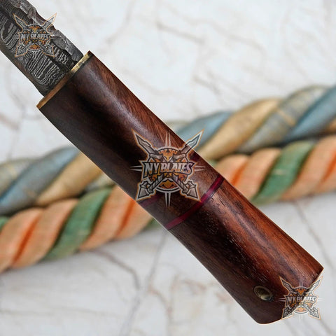 Close-up of Damascus Steel Fixed Blade Camping Knife With Walnut Wood Handle, showing brass bolster detail.