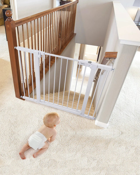Extra Wide Baby Gate For Stairs And Doorways, Auto Close, mounted at top of staircase with baby in diaper on carpeted floor.