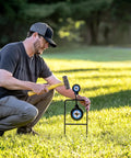 Person sets up Beefy Handgun Rebar Spinner Steel Target For 9mm Through.45 Caliber Pistols in outdoor lawn