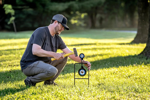 Person sets up Beefy Handgun Rebar Spinner Steel Target For 9mm Through.45 Caliber Pistols in outdoor lawn
