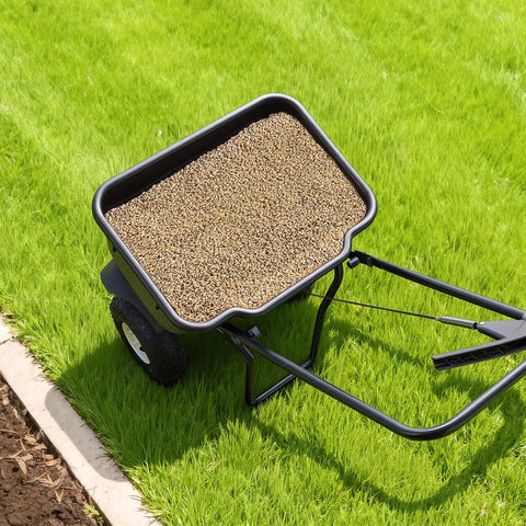 Push Lawn Spreader With 12 Foot Spreading Width, 80 Lb Hopper filled with seed, on grass, all terrain 10 inch tires visible, walk behind use