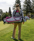 Woman carrying Women's X1 Complete Golf Club Set with driver, fairway, hybrid, irons, putter, stand bag, headcovers, graphite shafts.