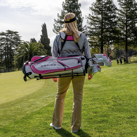 Woman carrying Women's X1 Complete Golf Club Set with driver, fairway, hybrid, irons, putter, stand bag, headcovers, graphite shafts.