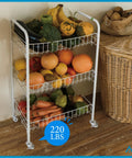 White three-tier metal rolling cart on caster wheels, loaded with oranges, apples, peppers, and other produce.