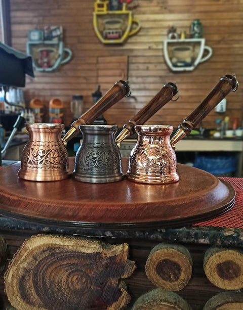 Three IST Series Thick Solid Copper Engraved Cezve For Stovetop Turkish Greek Arabic Coffee Pots on a wooden tray.